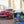 Ein rotes Auto, das auf einer Backsteinstraße in der Nähe von Gebäuden geparkt ist, präsentiert Produkte der ATG GmbH & Co. KG, wobei das ATG® Auto-Sparset Lack - Pflege DUO prominent im Vordergrund abgebildet ist.